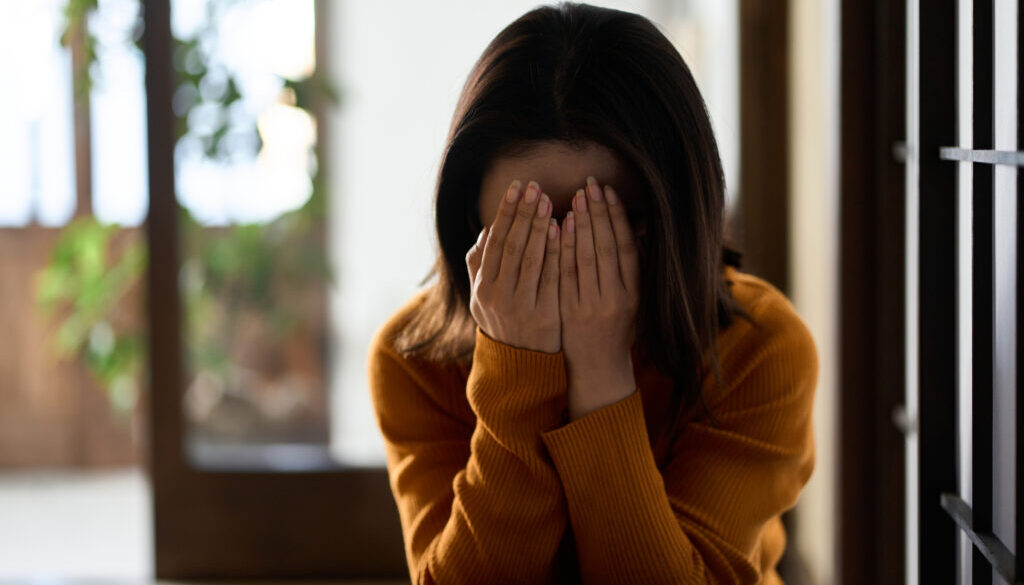 woman covering her face with both hands
